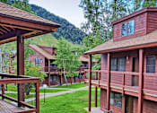 Thumbnail 1 of 17 - A mountain is behind a building with red siding.