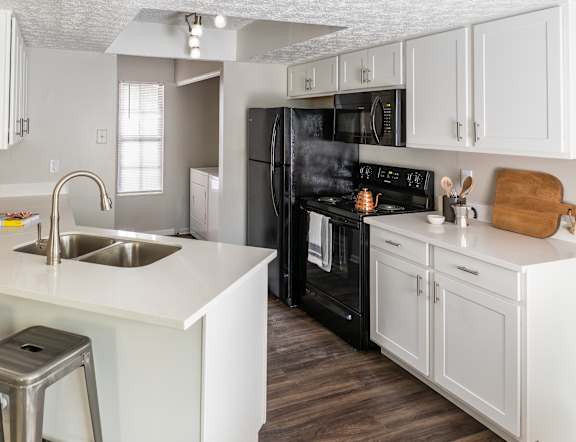 A kitchen with white cabinets and a black refrigerator.