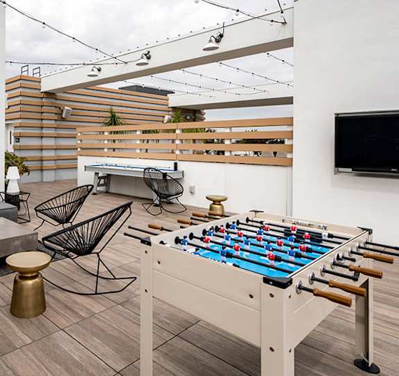 A foosball table is in the middle of a room with a couch and a TV. at Baker Block, California