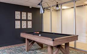 A pool table with a black cloth and white balls is in the center of the room.