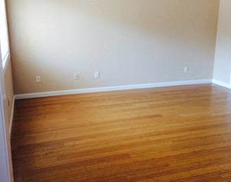 A room with a ceiling fan and wooden flooring.