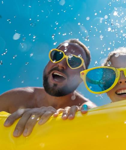 three people wearing sunglasses in the water with a yellow raft