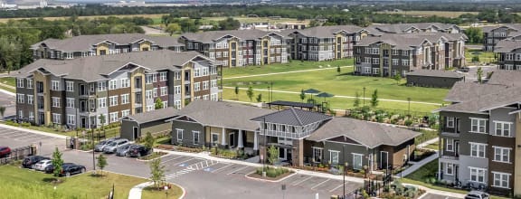 an aerial view of a large apartment complex with a parking lot and grassy area