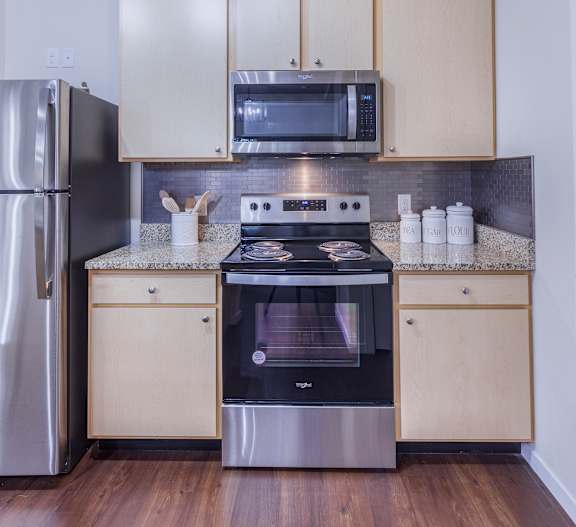 A modern kitchen with a stainless steel refrigerator, microwave, and oven.