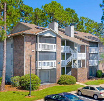 an apartment building with cars parked in a parking lot
