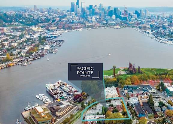 An aerial view of a city with a body of water and a sign that says Pacific Pointe Apartments.