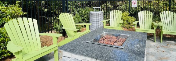 a fire pit with four green adirondack chairs around it