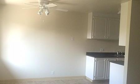 an empty living room with a ceiling fan