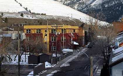 A snowy mountain range behind a yellow building with a sign that says "Village Hall".