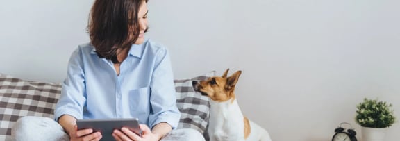 a woman sitting on a bed with her dog 