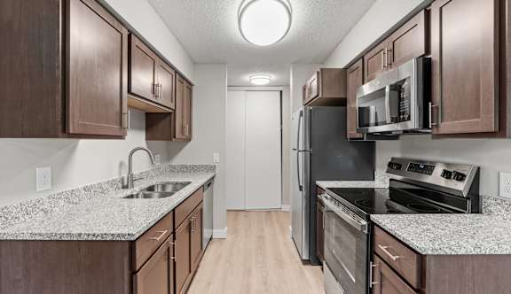 A kitchen with brown cabinets and black appliances.