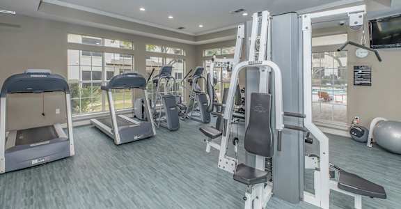 a gym with cardio equipment and a window