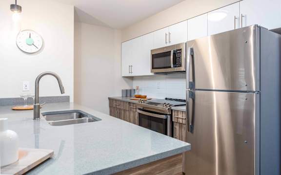 A kitchen with a stainless steel refrigerator, microwave, and sink. at G17 Apartments at Tamarack, Edmonton, T6T 2M4