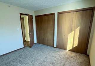 a bedroom with a carpeted floor and two side-by-side closets