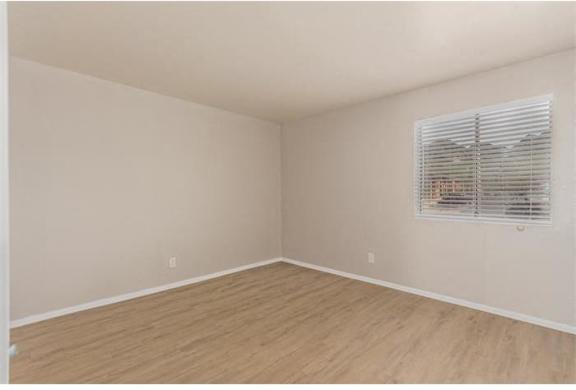 an empty room with a window and wood floors