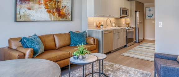 a living room with a couch and a table and a kitchen in the background