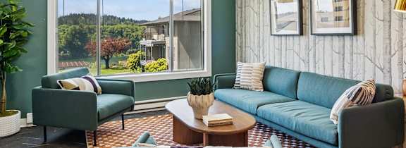 A living room with a green couch and a grey armchair.