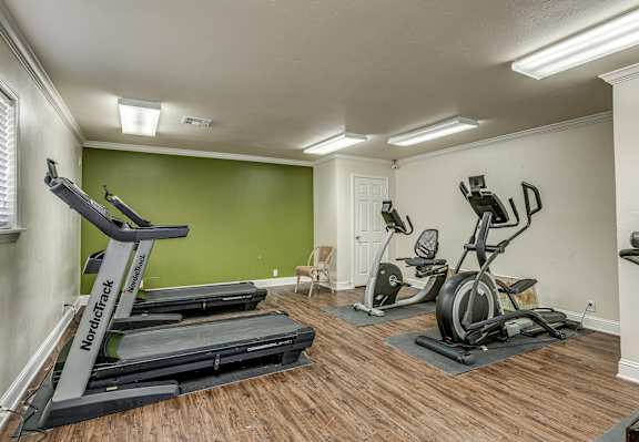A home gym with a NordicTrack treadmill, a stationary bike, and a treadmill.