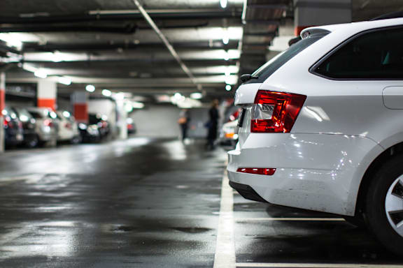 A white car is parked in a dimly lit parking garage.