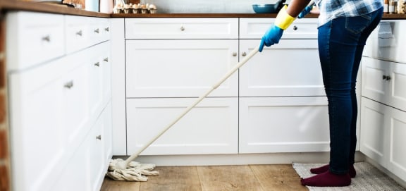 a woman is mopping the floor in the kitchen
