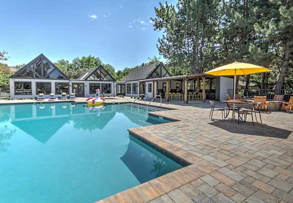 A large outdoor swimming pool with a yellow umbrella and a house in the background.