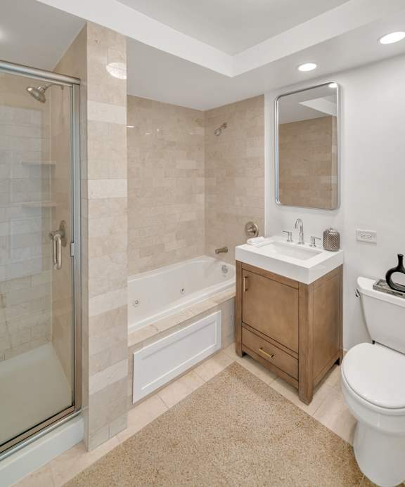 A bathroom with a white toilet, a sink, a mirror, and a glass shower door.