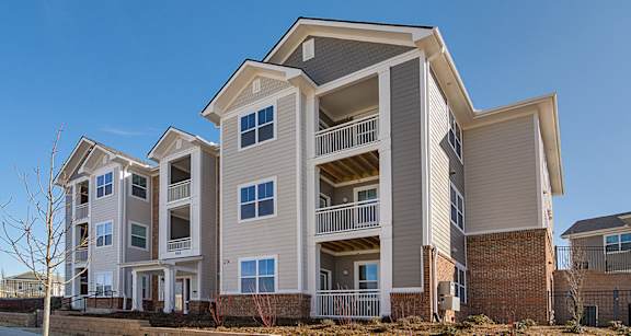 A modern apartment building with multiple balconies and a clear blue sky.