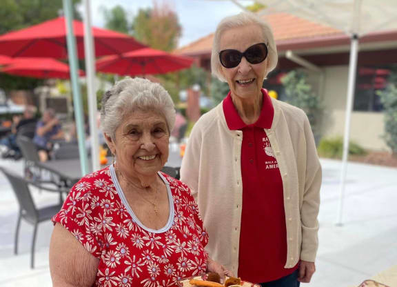 two women standing next to a table of food