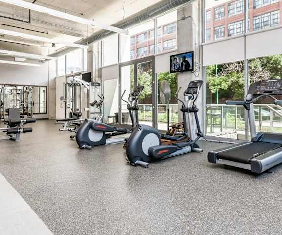 a gym with cardio equipment and windows in a building