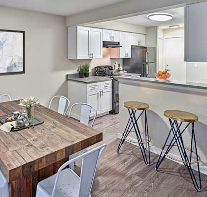 a dining area with a table and chairs and a kitchen in the background with bar stools.at Arterra, Kent, WA 98030