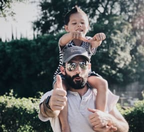 Man in white t-shirt carrying boy on his shoulders
