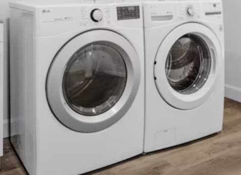 Two white front load washing machines in a laundry room.