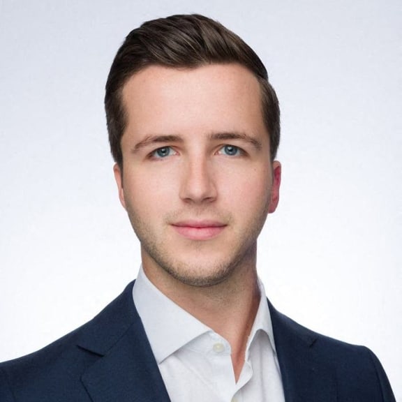 A man with short hair and a blue suit jacket.