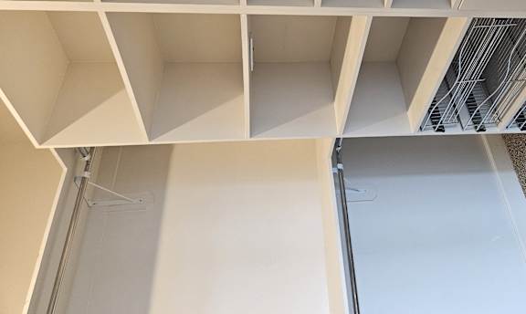 A white shelving unit with a white door and a white wall.