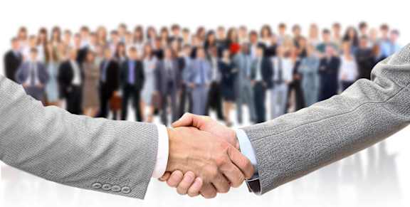 Two people shaking hands in front of a crowd.