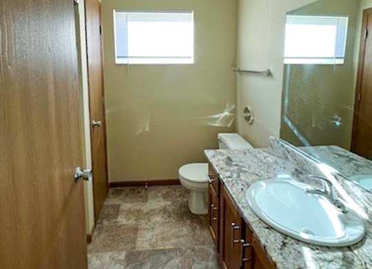 a bathroom with a vanity sink, a mirror, a linen closet, and a window
