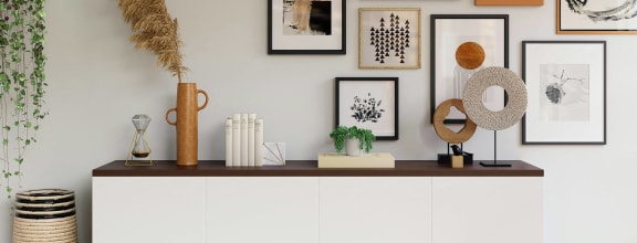 a white credenza with pictures on the wall above it in a living room