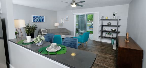 View from kitchen to living room in Mandarin Bay apartments in Jacksonville, FL. Living room is large with blue and grey midcentury seating.