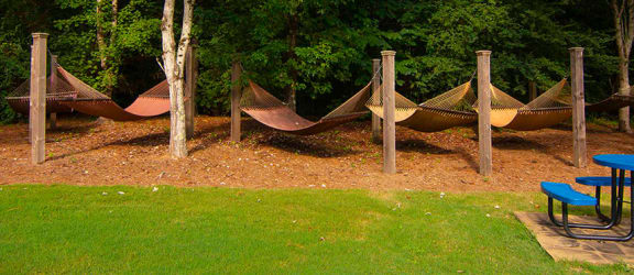 a group of hammocks in a park with tables and chairs