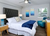 Thumbnail 5 of 23 - Mandarin bay apartment bedroom in Jacksonville, FL with large bed, sitting chair, window with slat blinds, and midcentury wooden dresser.