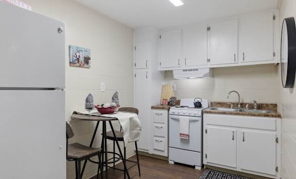 A kitchen with white cabinets and a white refrigerator.