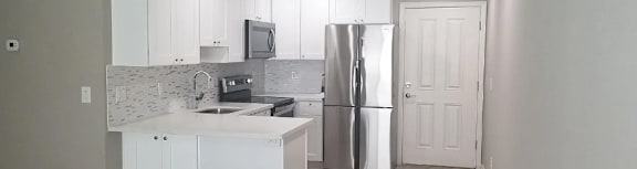 A kitchen with white cabinets and a stainless steel refrigerator.