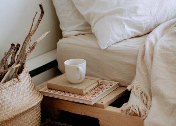 A tray with books and a cup of coffee placed next to a bedroom.