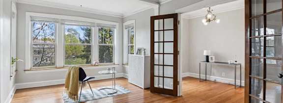 A room with a wooden floor and a window overlooking a green lawn.