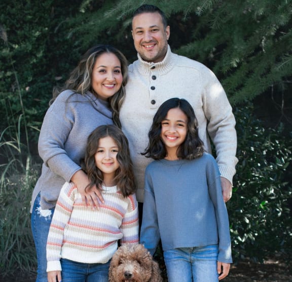 a family of four and their dog pose for a picture in front of a christmas tree