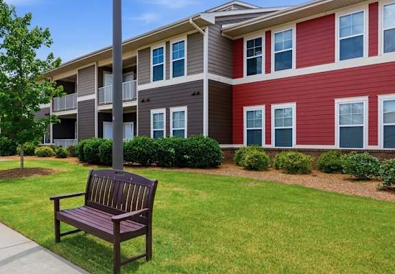 A bench sits on a sidewalk in front of apartment buildings.