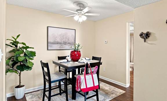 A dining room with a table, chairs, and a ceiling fan.
