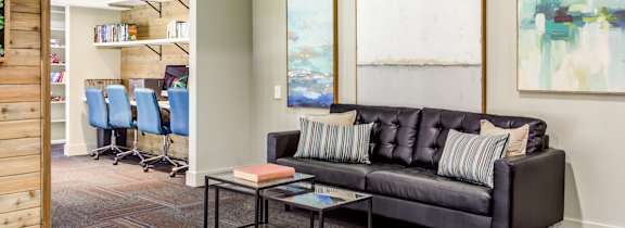 A living room with a grey couch, a coffee table, and a painting on the wall.