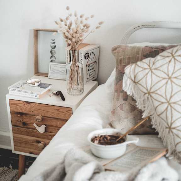 Bedroom featuring a bed and a nightstand with a vase of flowers.