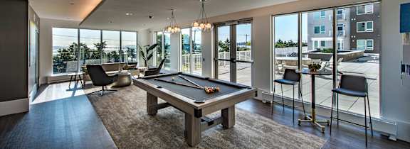 A billiard table is in the middle of a room with a view of the outside.